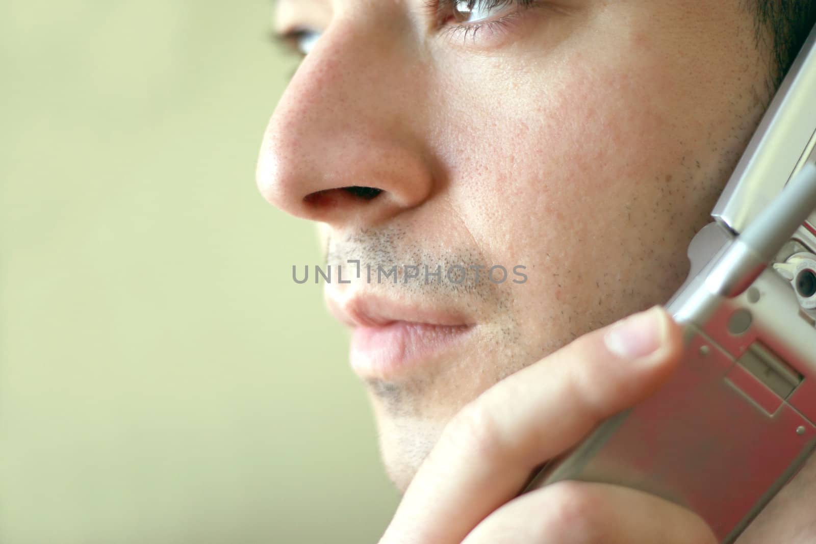 Portrait of a young man on his cell phone.  He is listening with a  serious look of concern on his face.