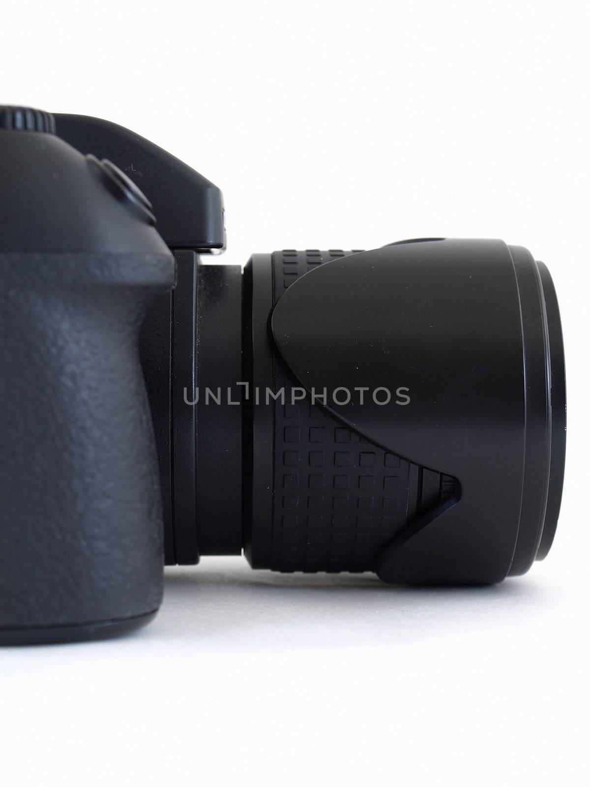 A black digital camera body with an attached lens. Studio isolated over white.