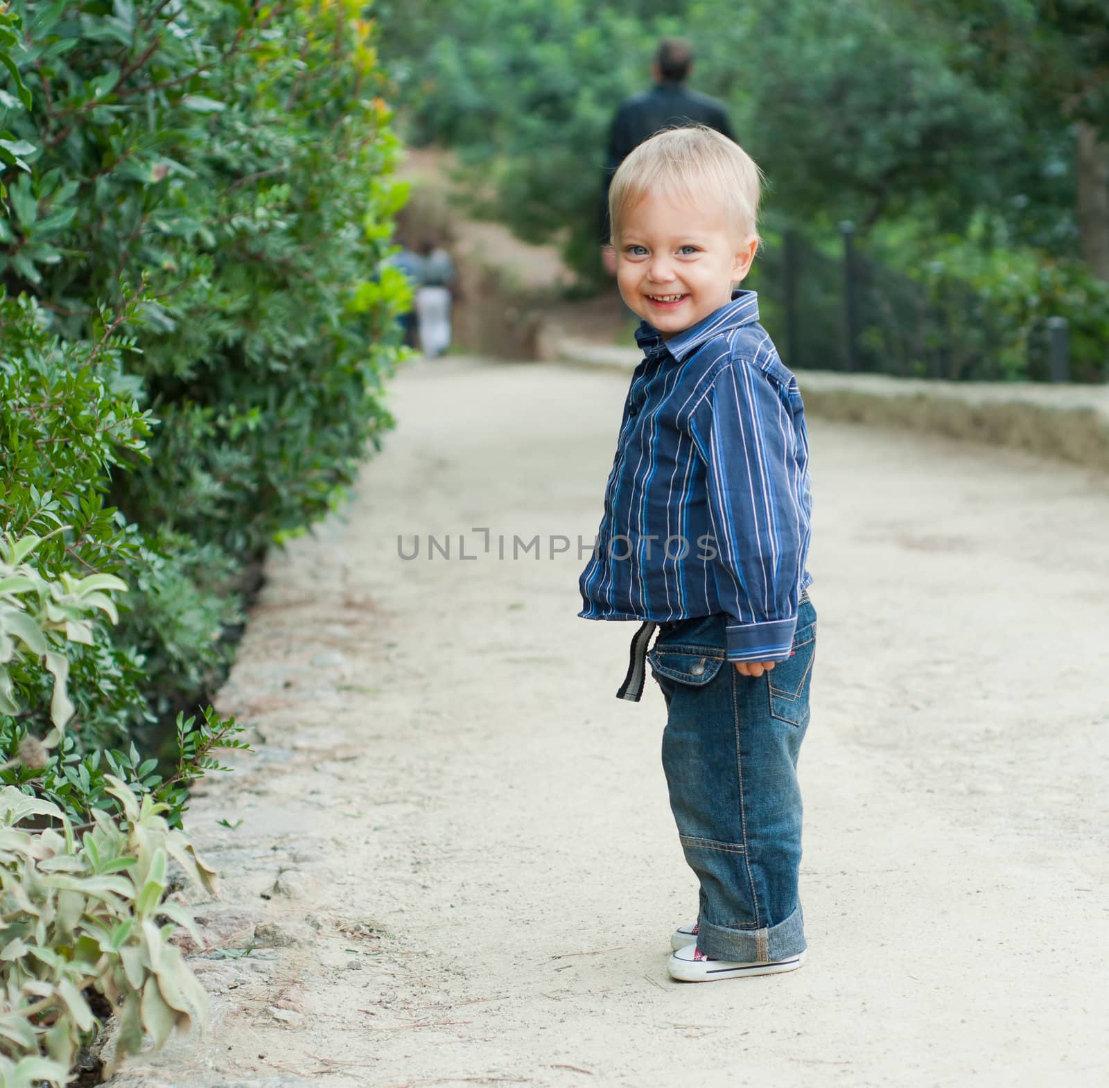 Cute 2 years old boy standing on the footpath in the park