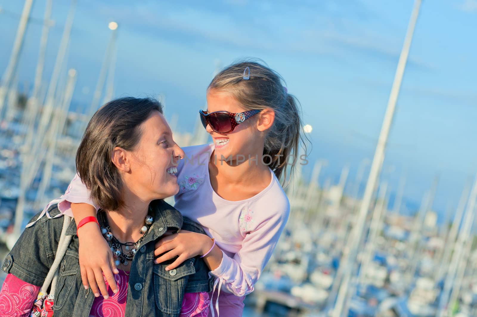 Closeup Portrait of a cute girl with her mother in the background of yachts