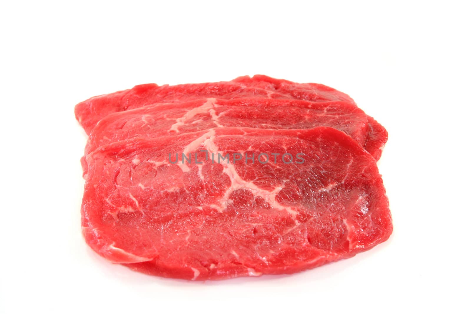 three raw beef minute steaks on a white background