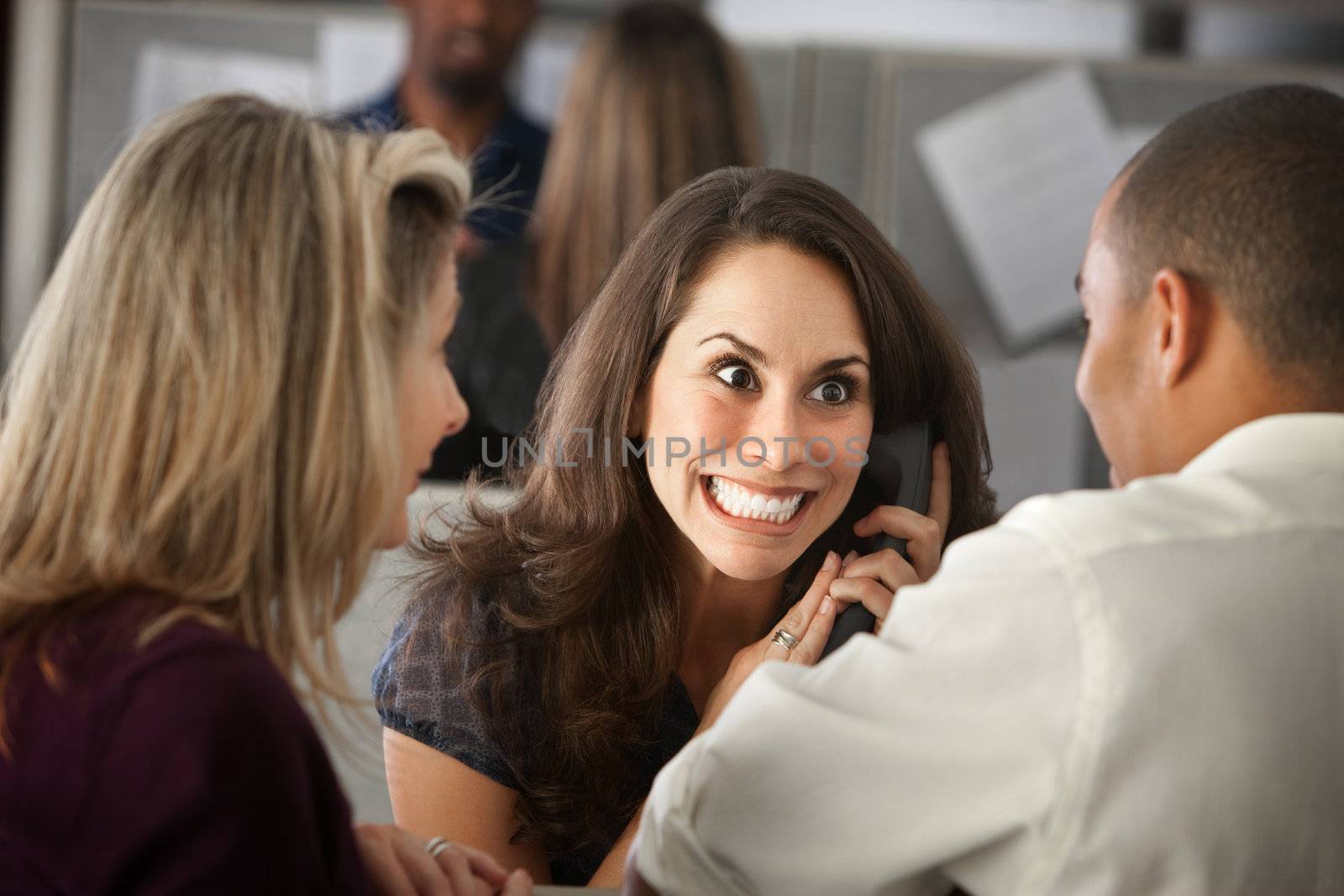 Excited woman office worker with colleagues on phone