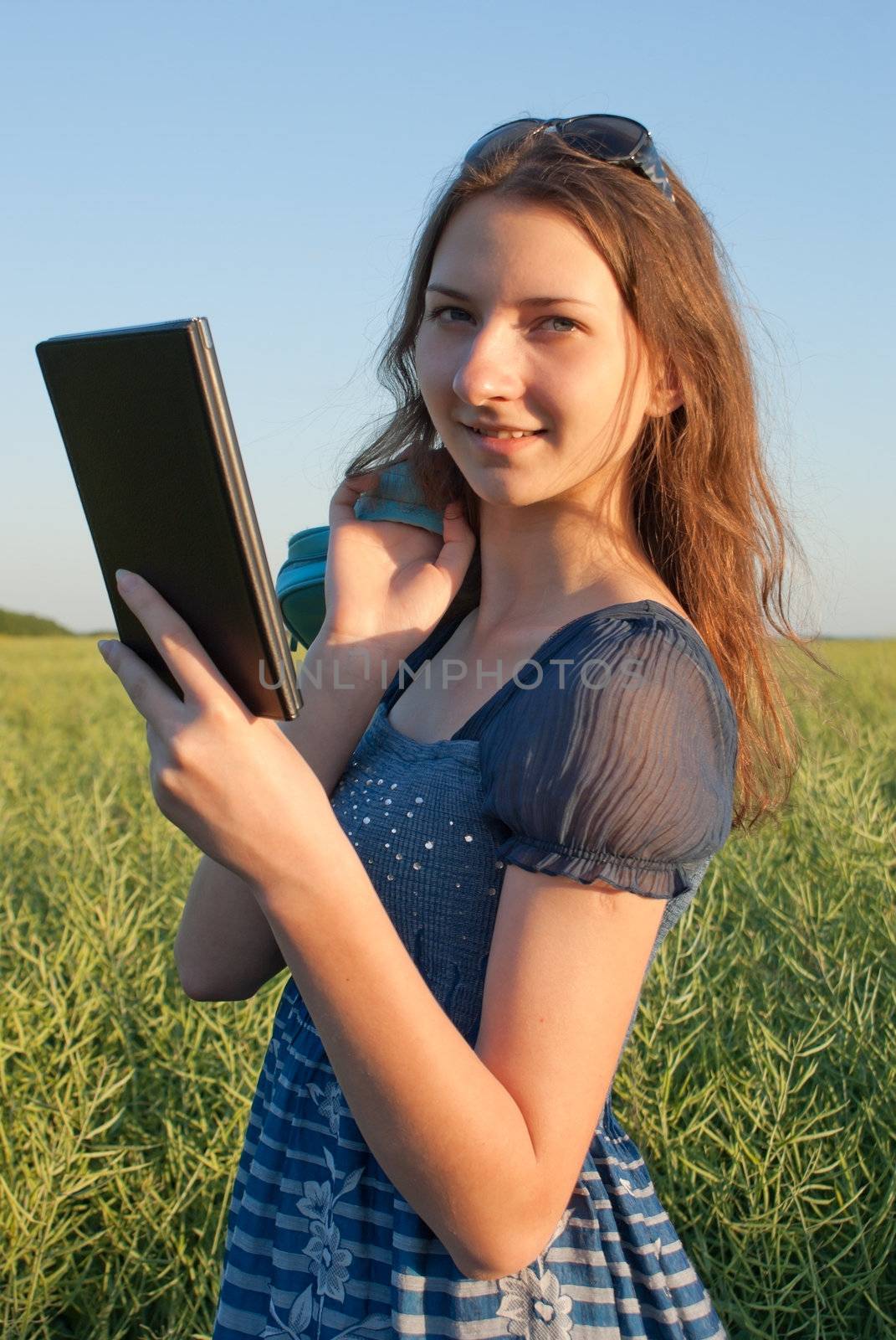Teen girl with electronic book reader outdoors by AndreyKr