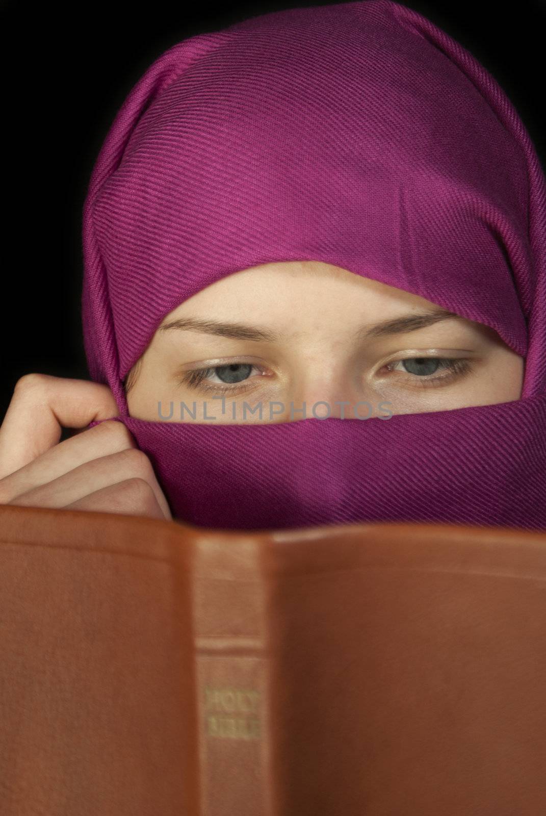 Teen girl muffled in a shawl readingg the Bible