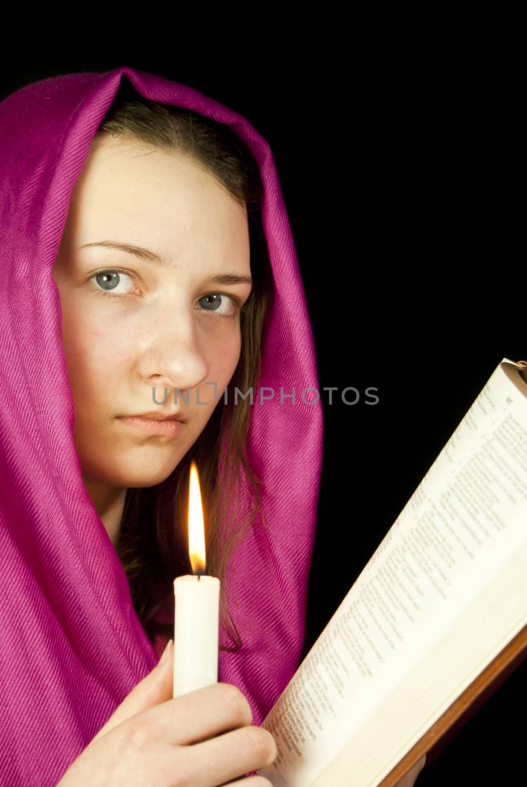 Eastern style dressed teen girl with a candle and the Bible