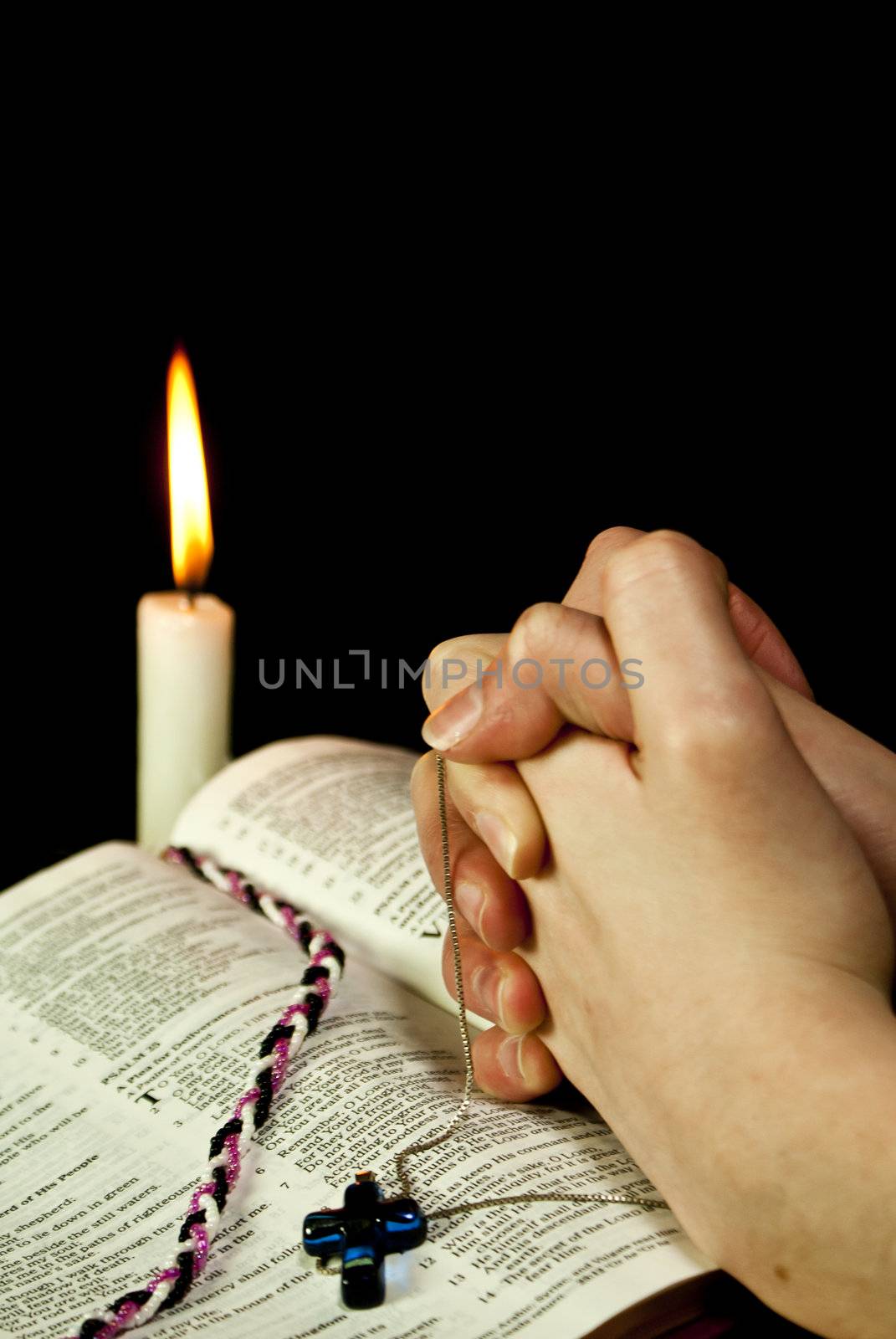 Open Bible with burning candle and hands of praying woman by AndreyKr