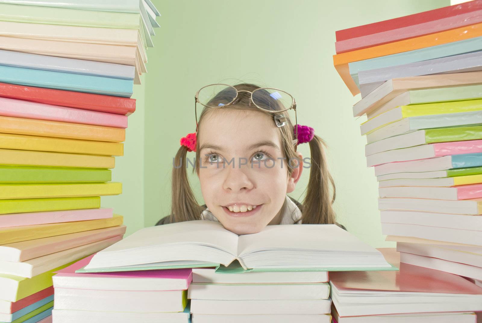 School girl sitting at the table with stacks of books