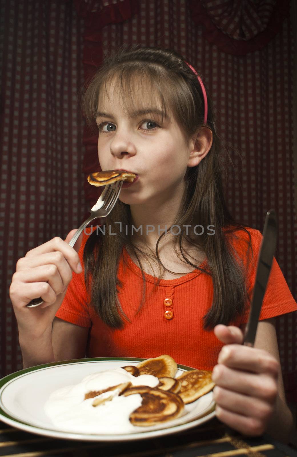 Teen girl eats a pancake from a dish
