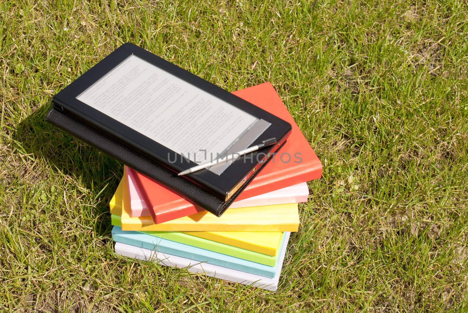 Ebook reader with a stack of books by AndreyKr