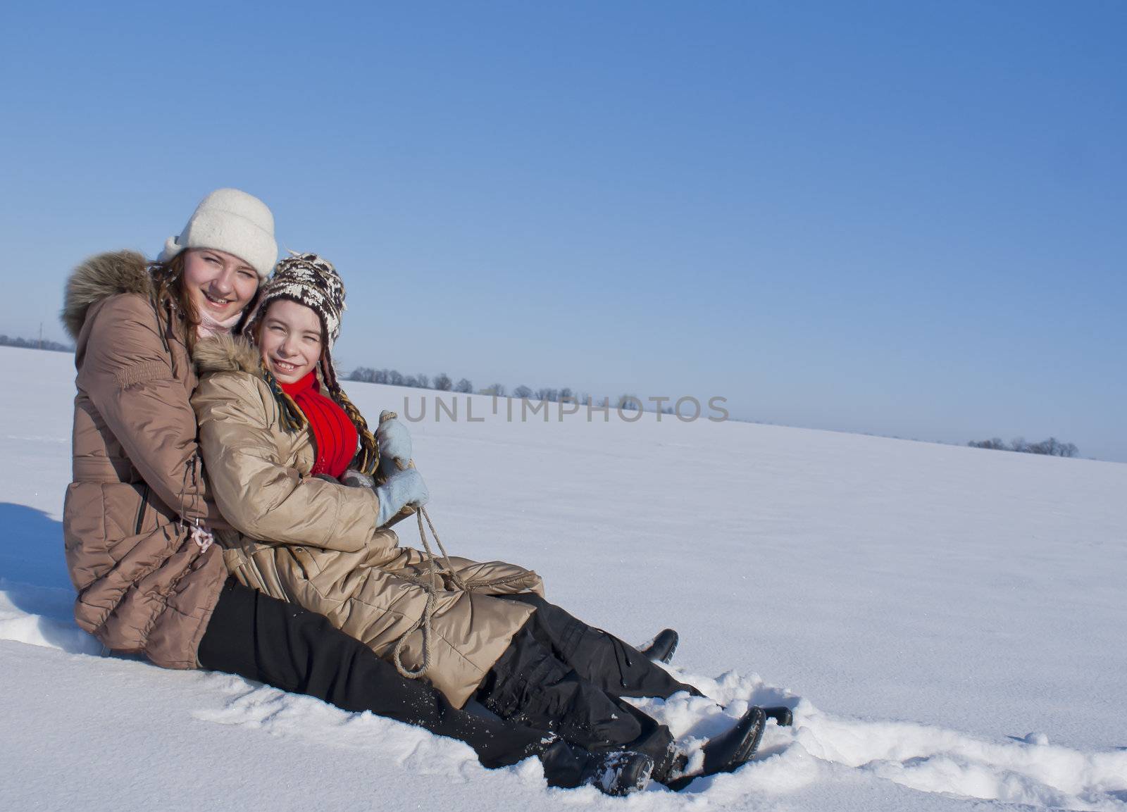Two happy sisters sledding at winter time by AndreyKr