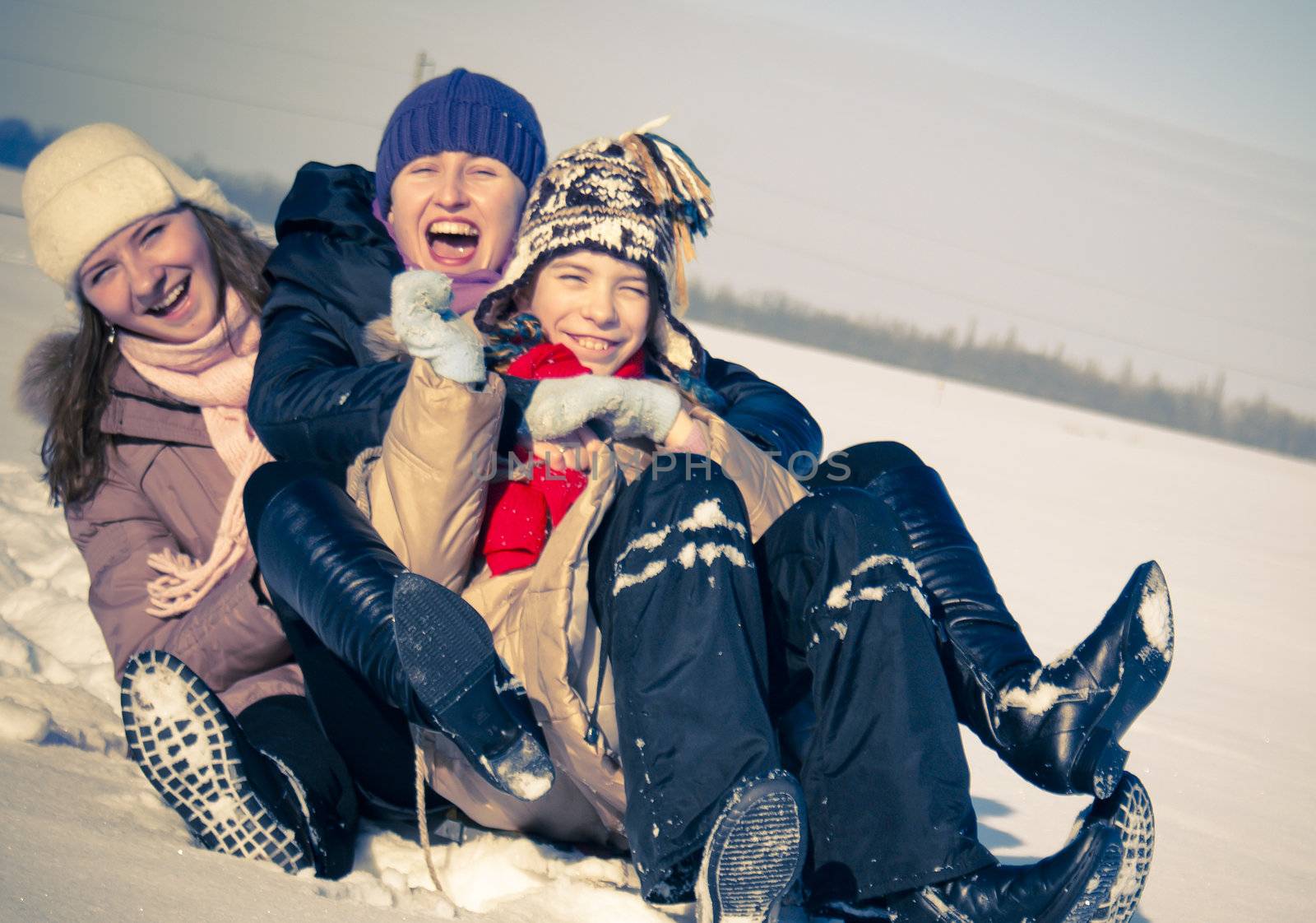 Three happy sisters sledding at winter time by AndreyKr
