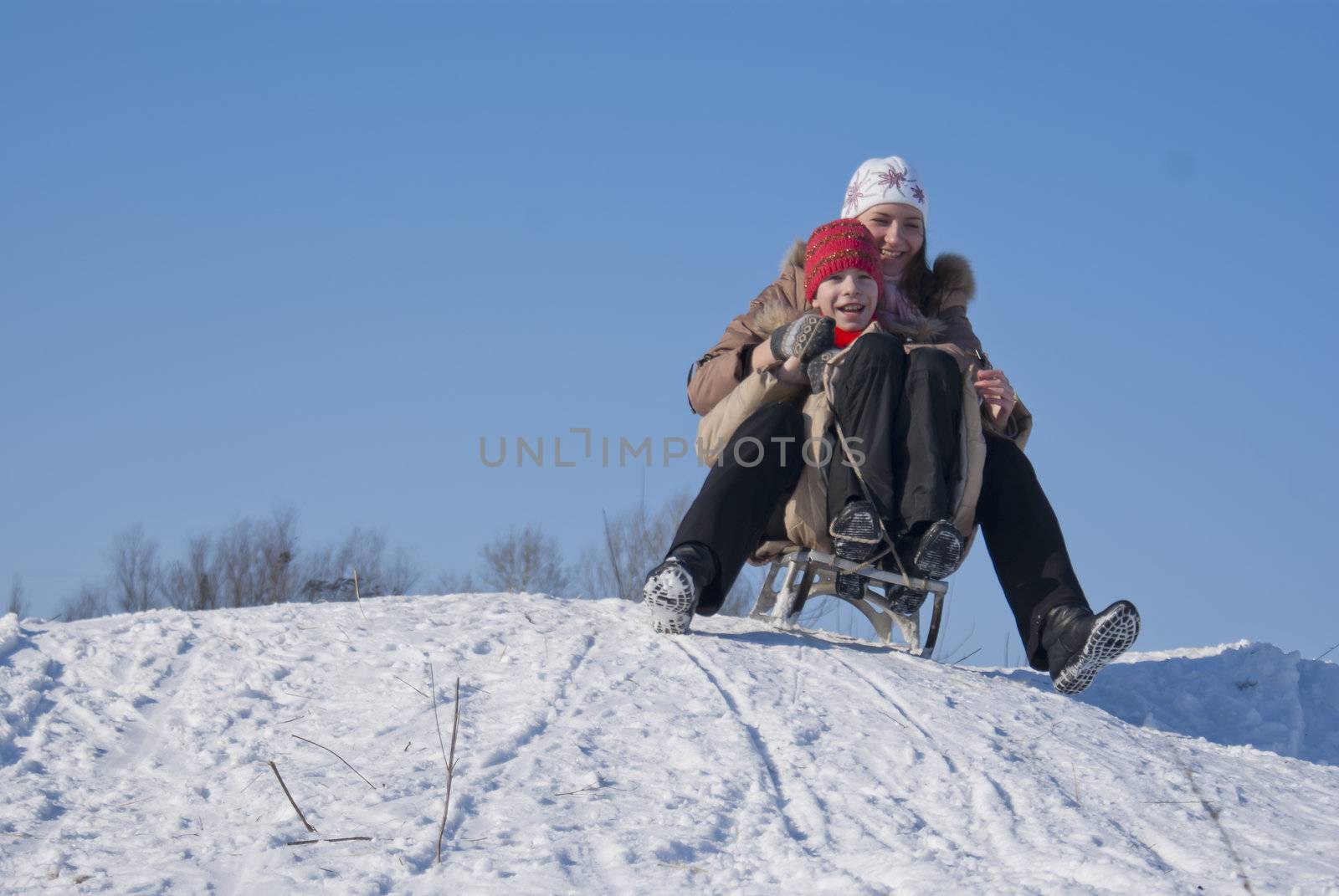Two happy sisters sledding at winter time by AndreyKr