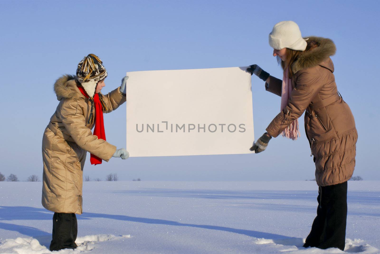 Girls holding white poster at winter snowy field by AndreyKr