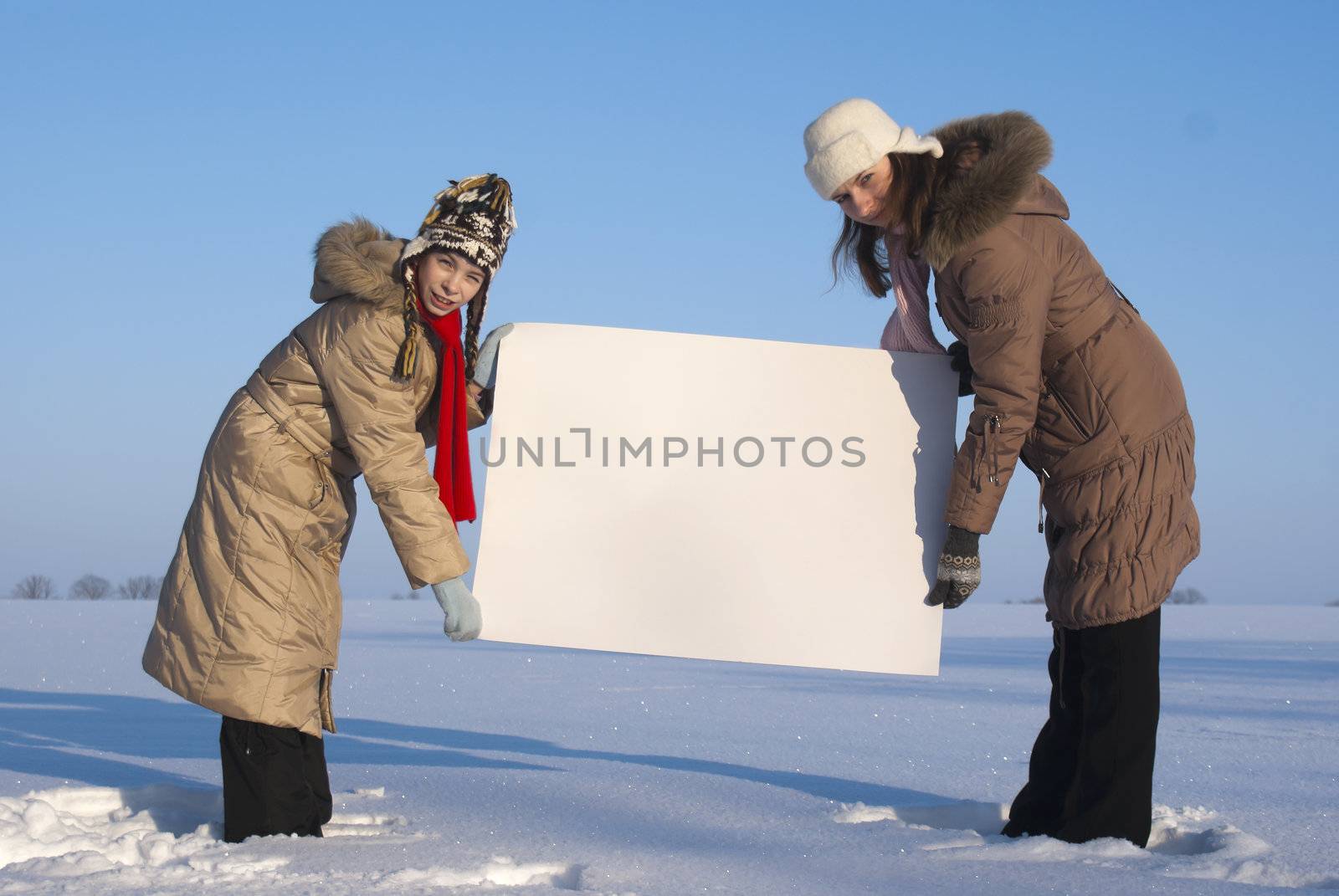 Girls holding white poster at winter snowy field by AndreyKr