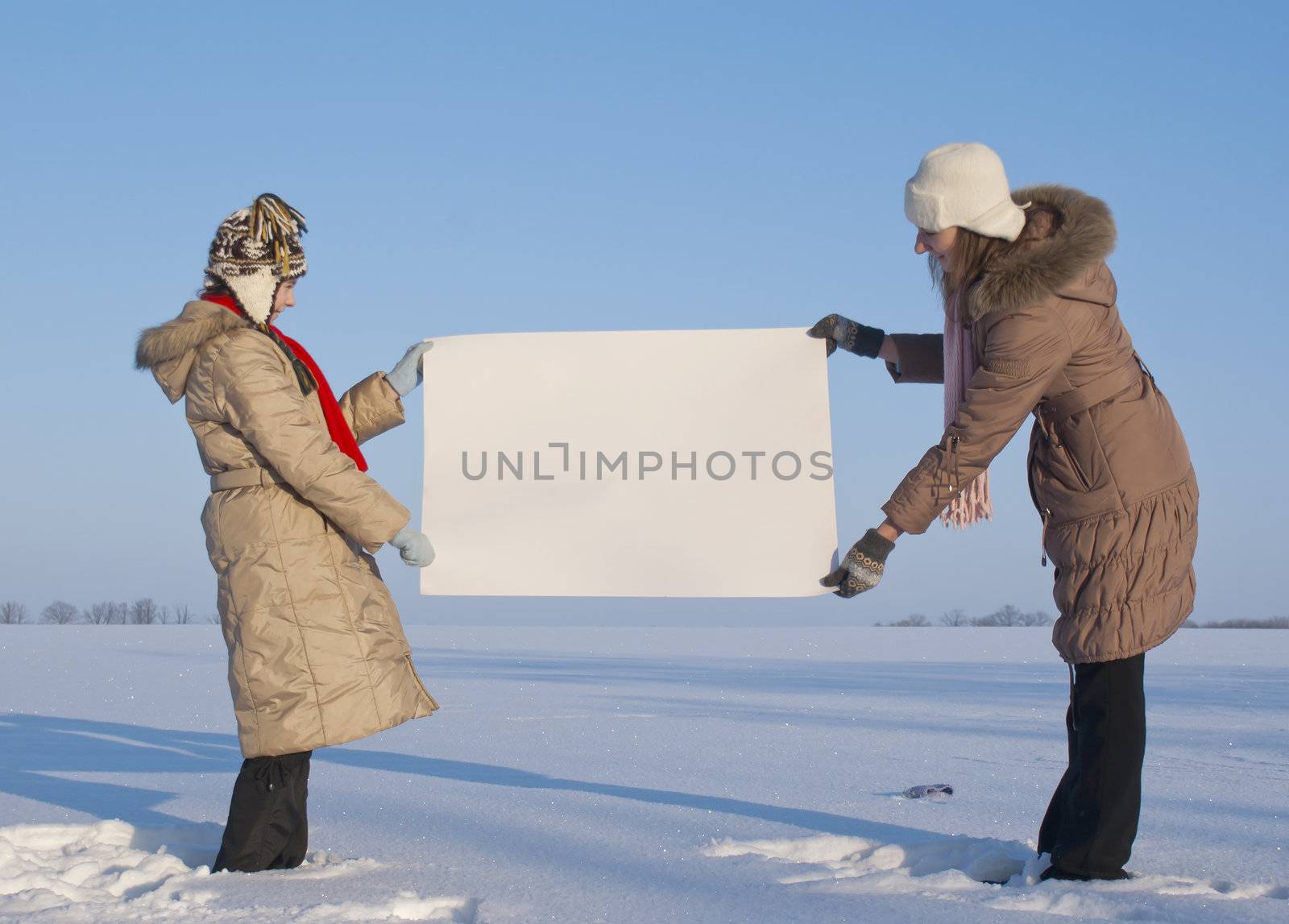 Girls holding white poster at winter snowy field