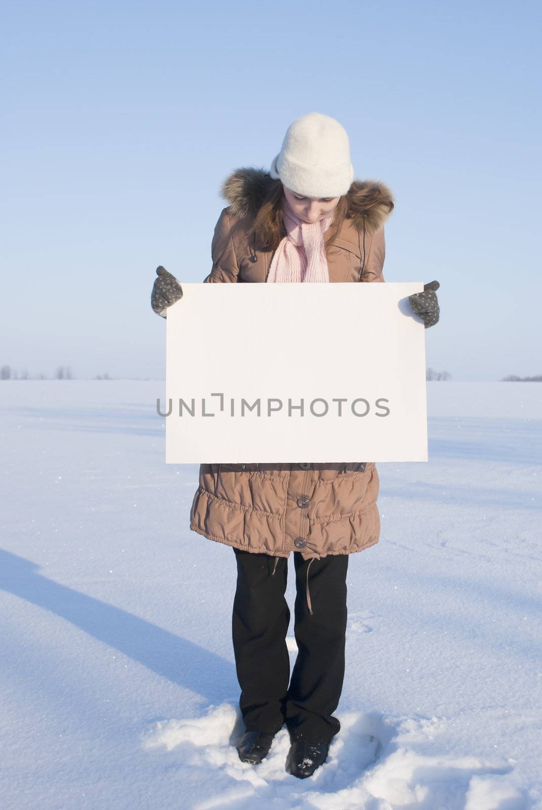 Girl holding white poster at winter snowy field