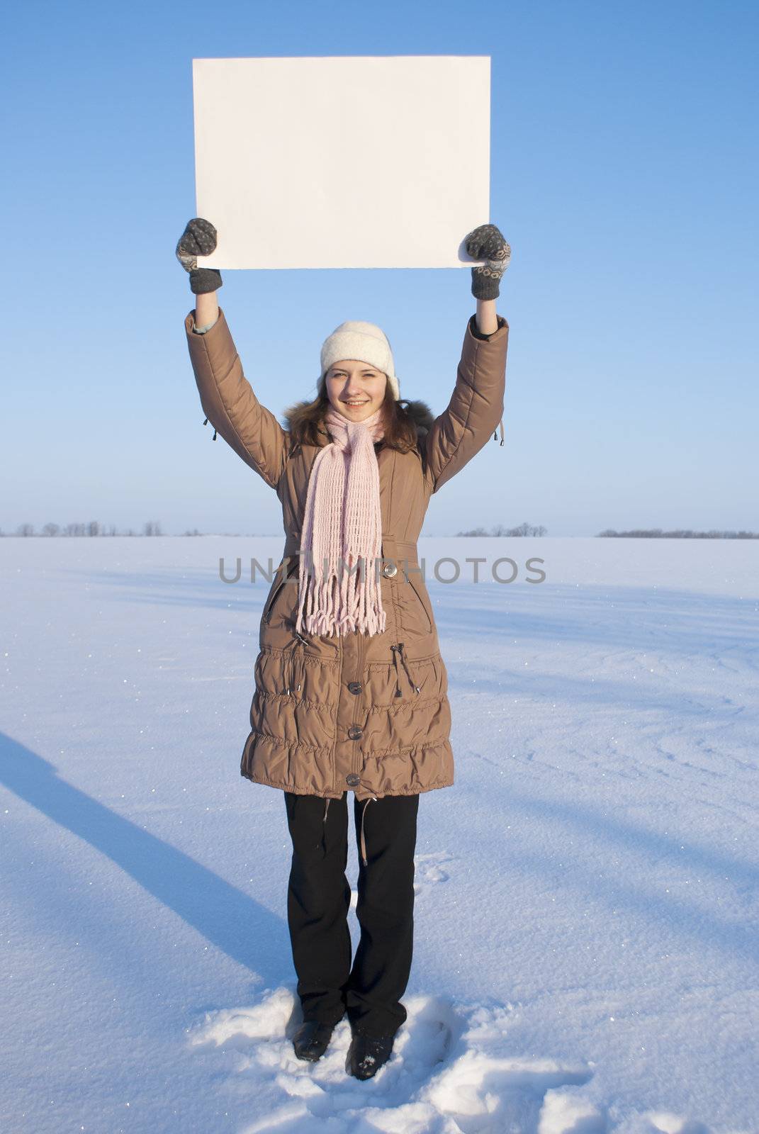 Girl holding white poster at winter snowy field