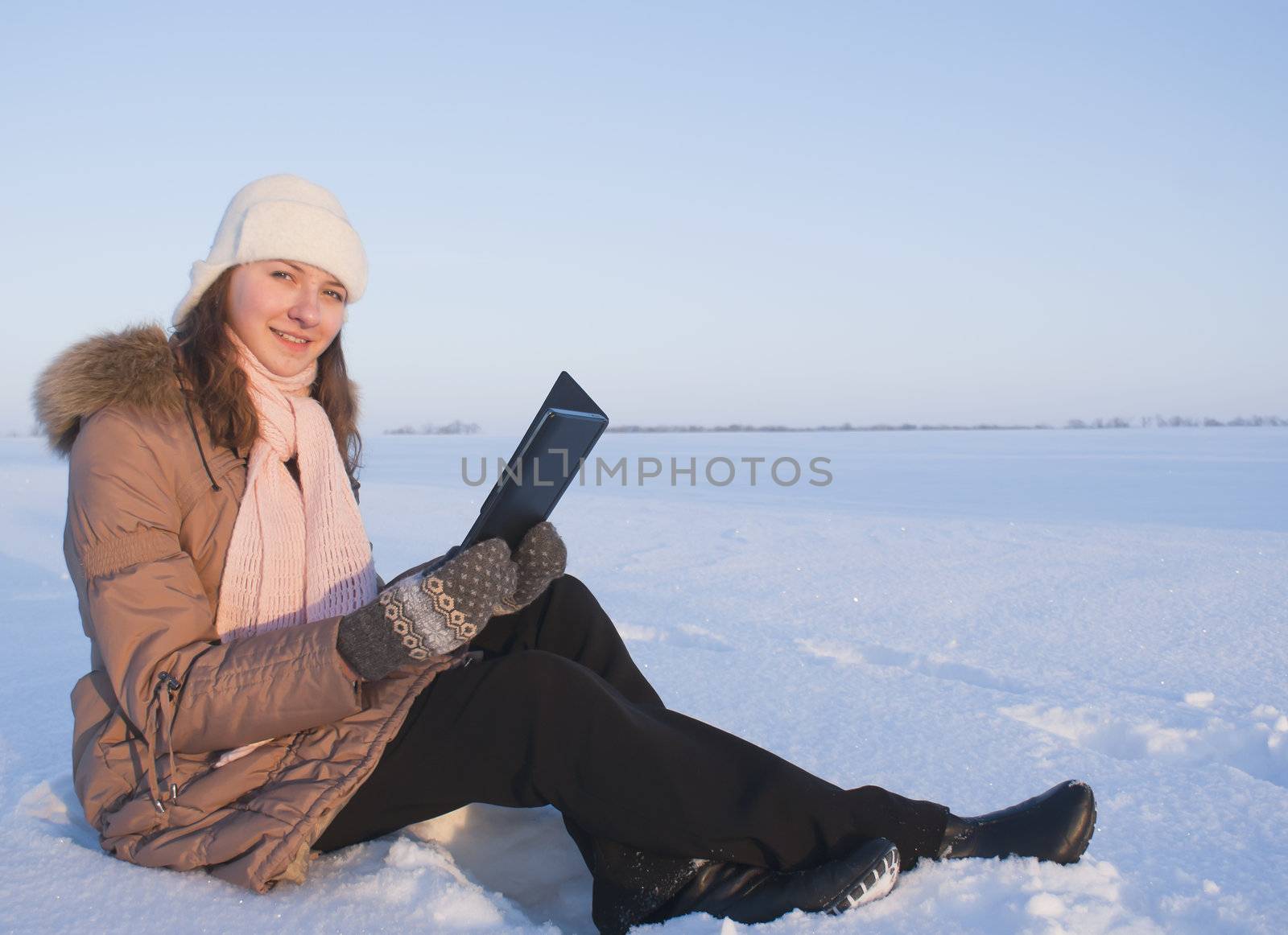 Teen girl reading e-book outdoors at winter time by AndreyKr