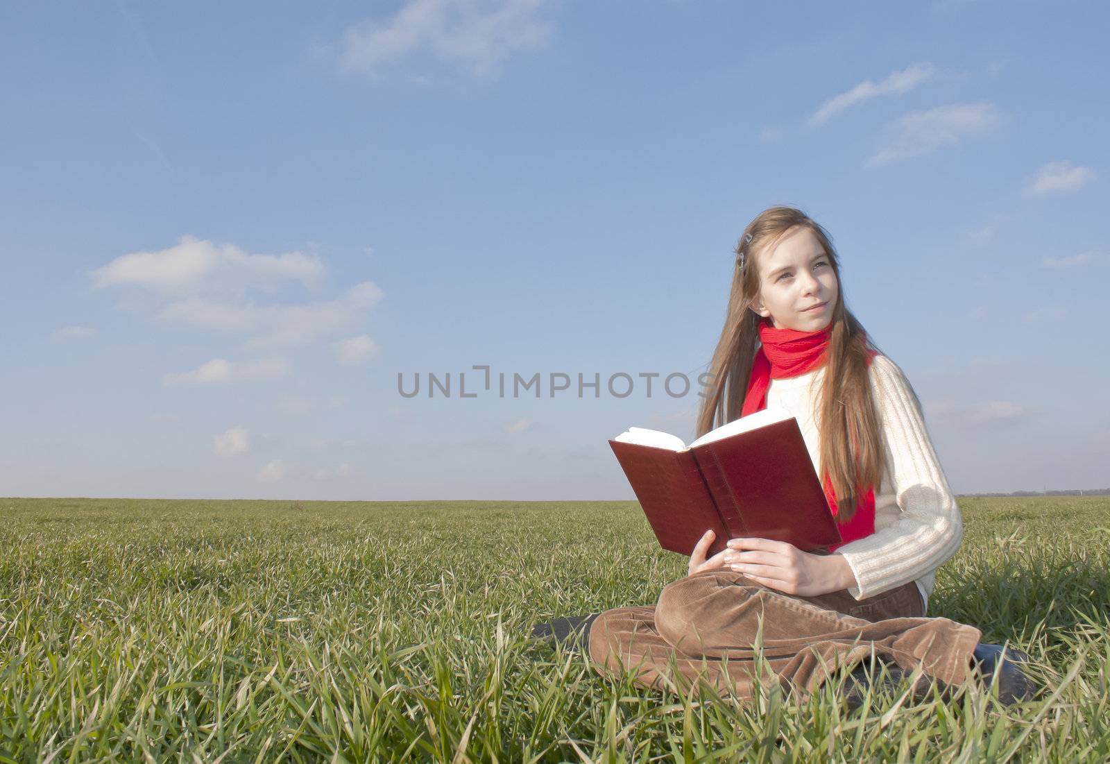 Girl reading a book sitting at grass by AndreyKr