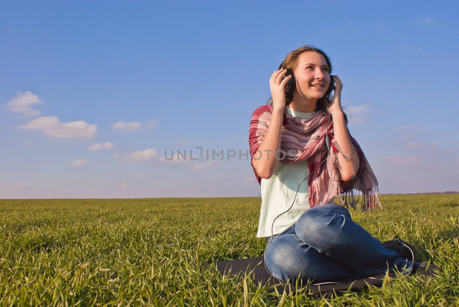 Girl with headphones listening music outdoors by AndreyKr