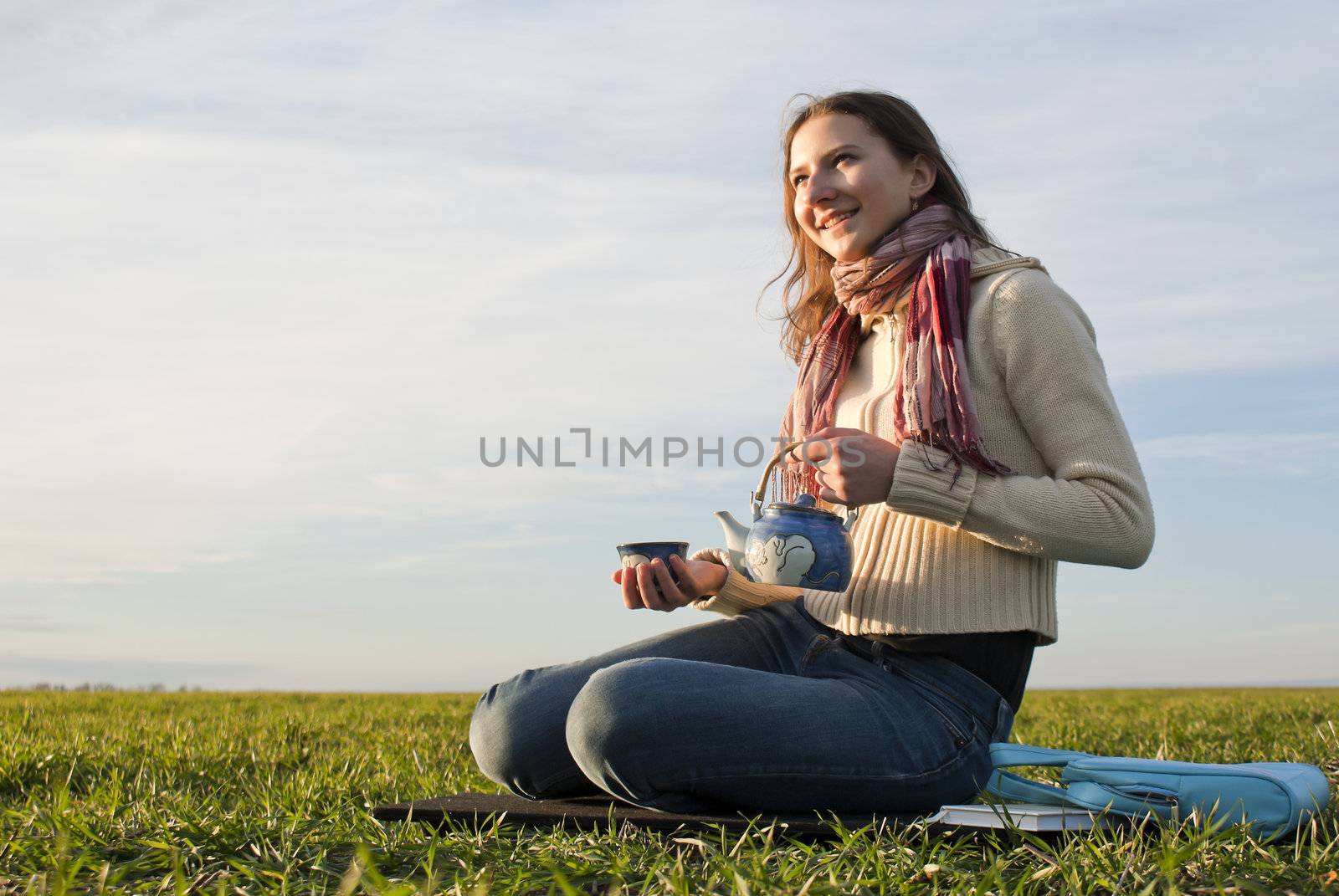 Girl with teapot sitting on grass by AndreyKr