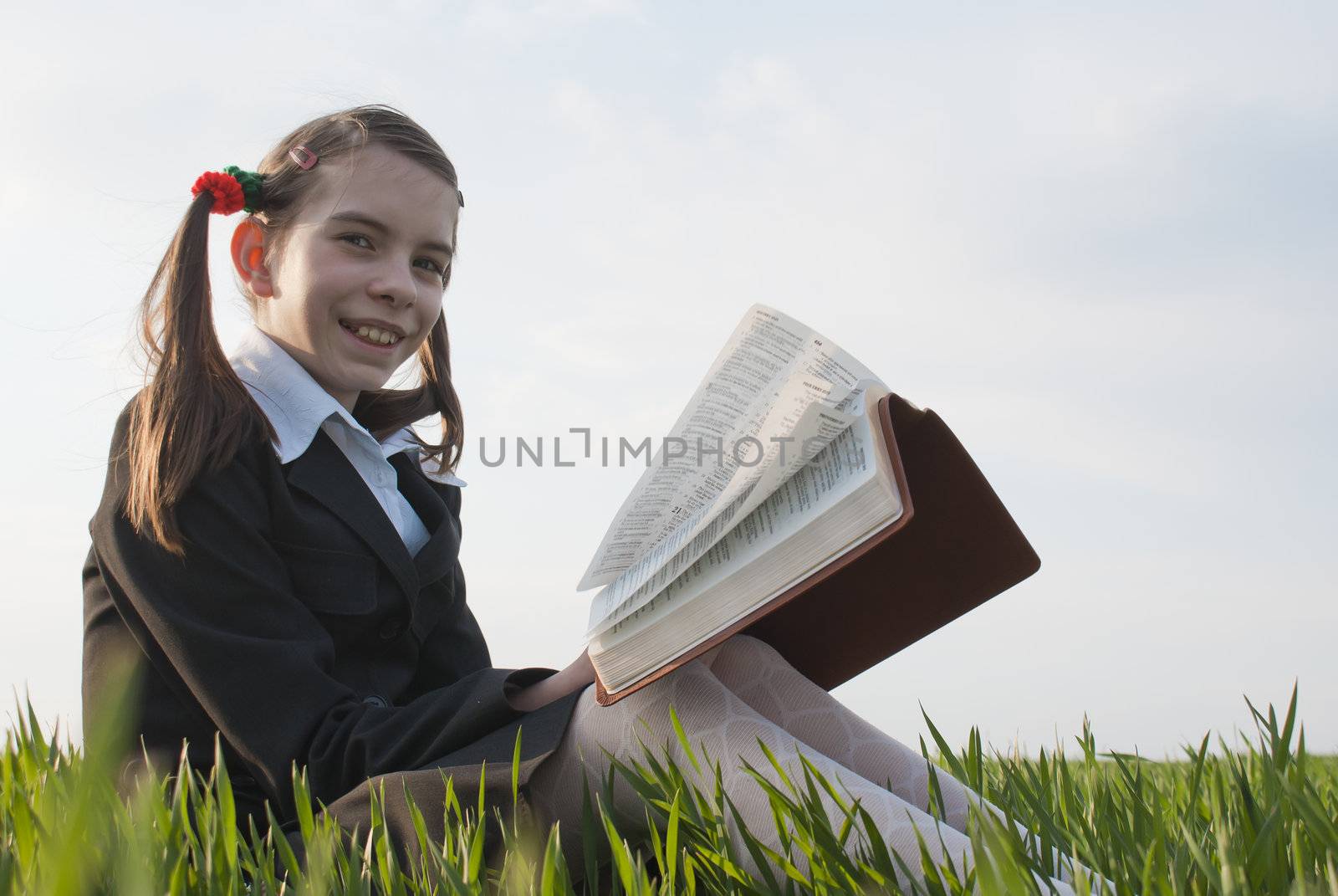 Girl with a book sitting on the grass