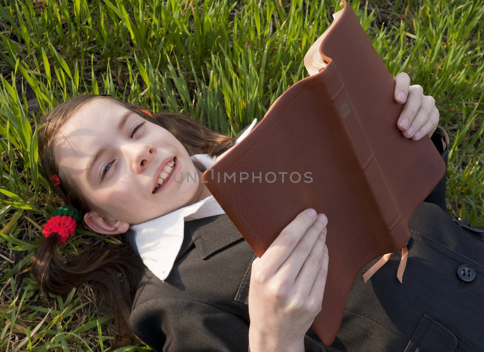 Girl with the Bible laying on the grass by AndreyKr