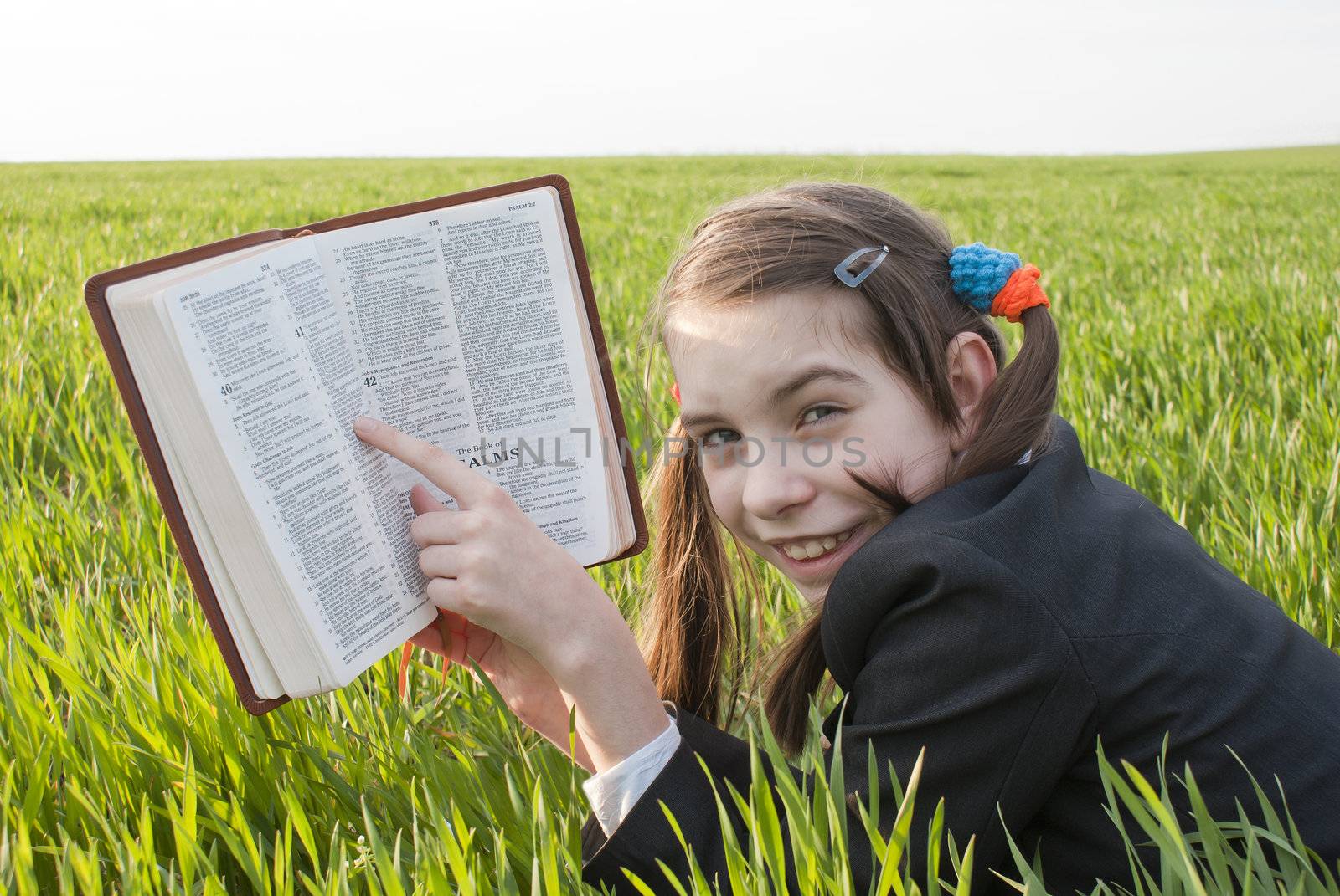 Girl with the Bible laying on the grass by AndreyKr