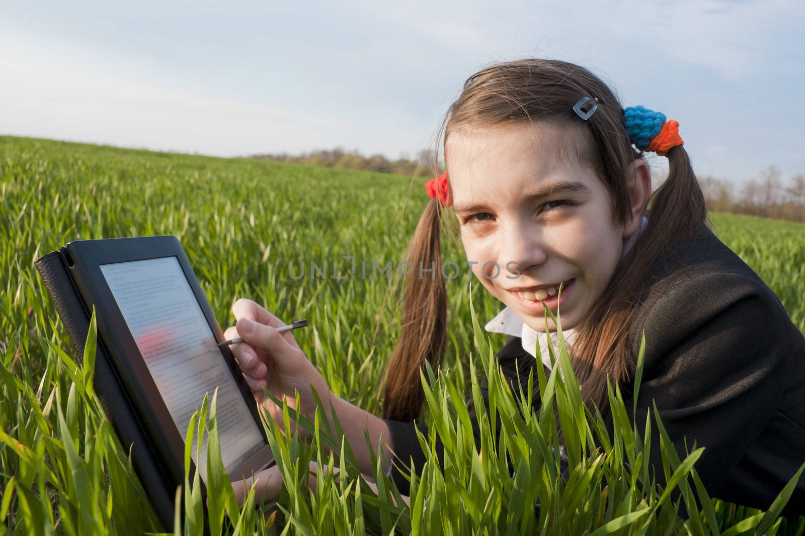 Teen girl with e-book reader laying on grass