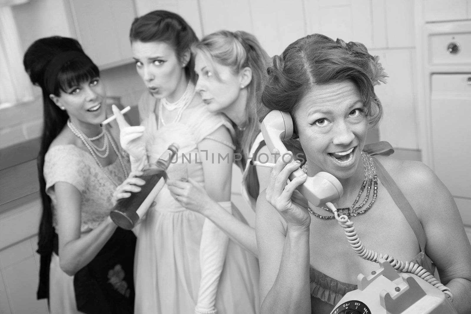 Excited woman on phone while friends drink and smoke in the kitchen