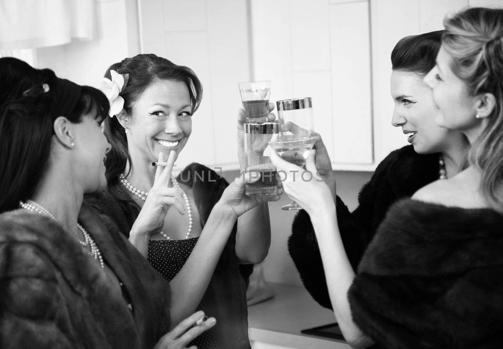 Group of four Caucasian women in a kitchen make a toast