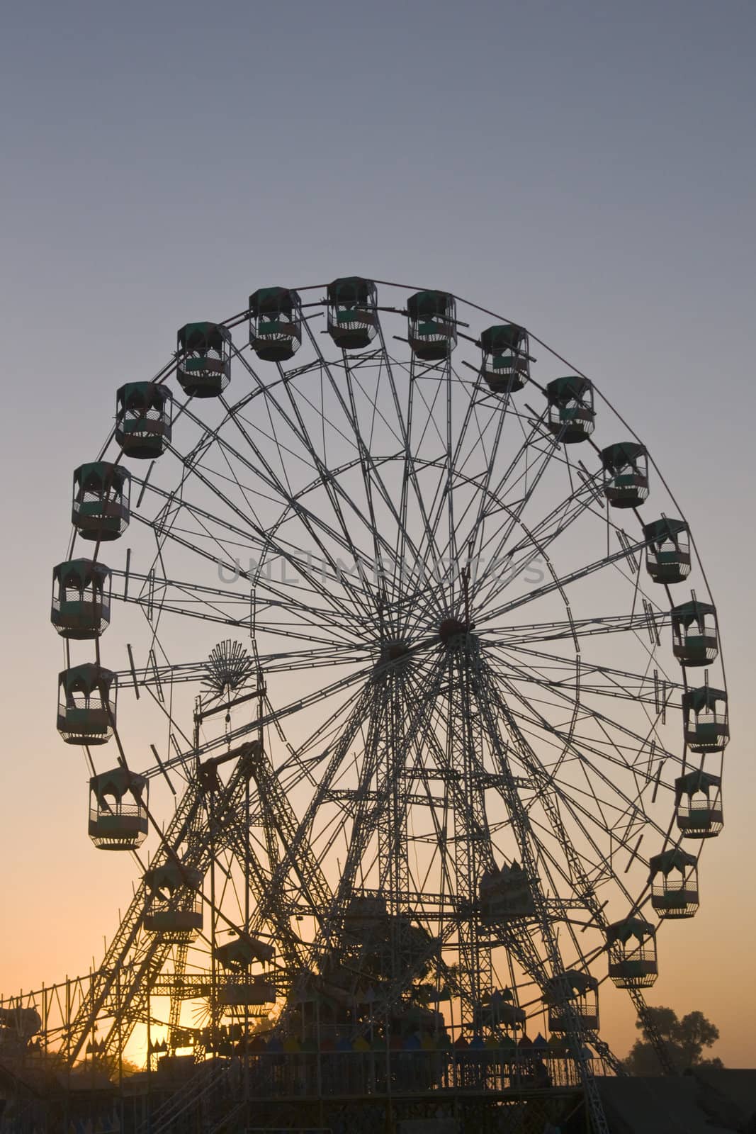 Ferris wheel silhouetted against the darkening sky as the sun sets over the Pushkar fair in Rajasthan, India