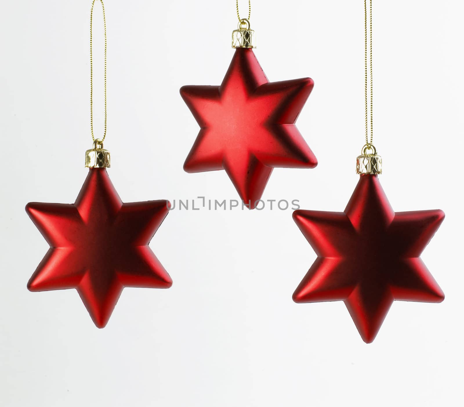 Three red Christmas Stars hanging on white background