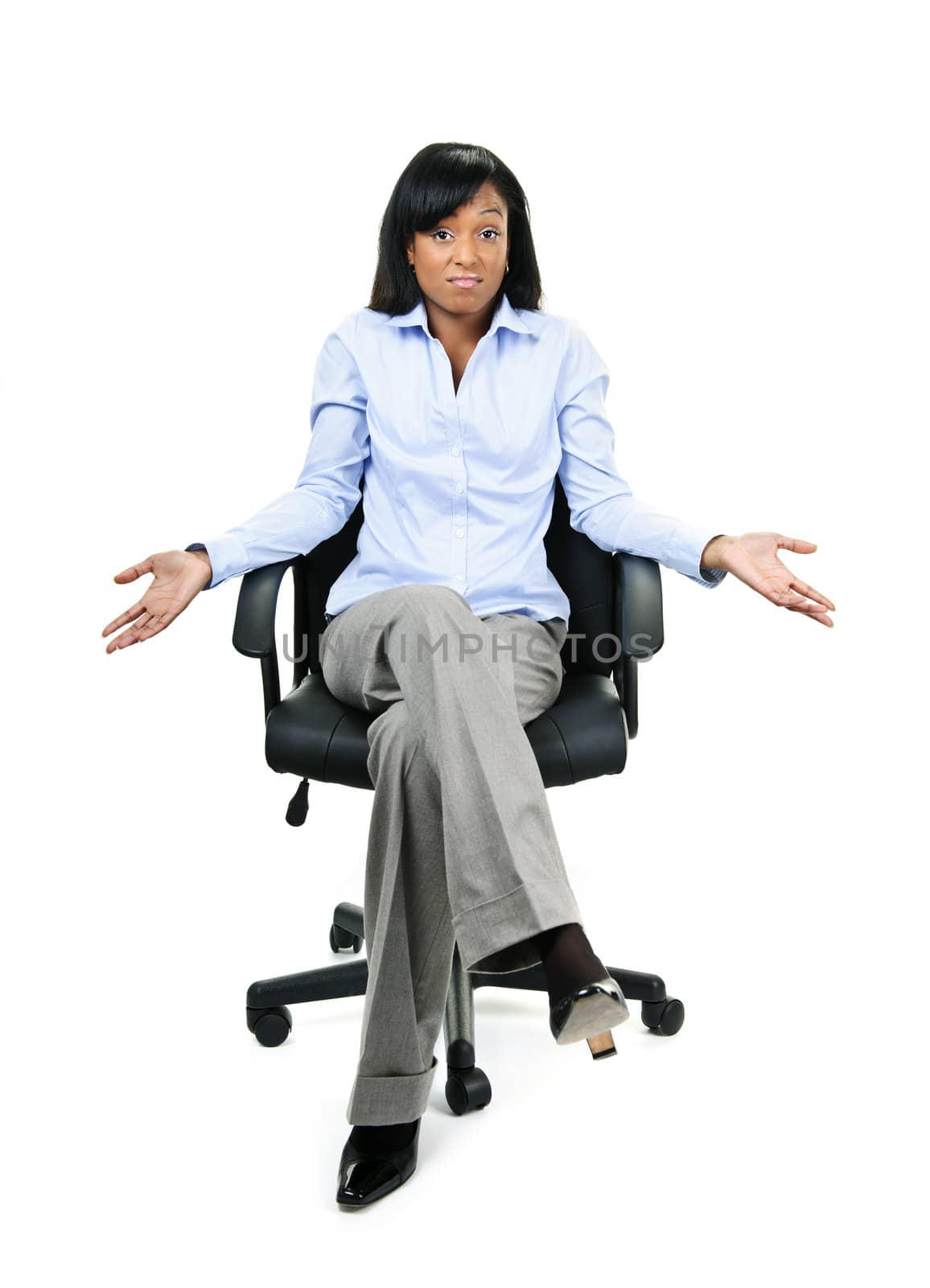 Young shrugging confused black businesswoman sitting in leather office chair