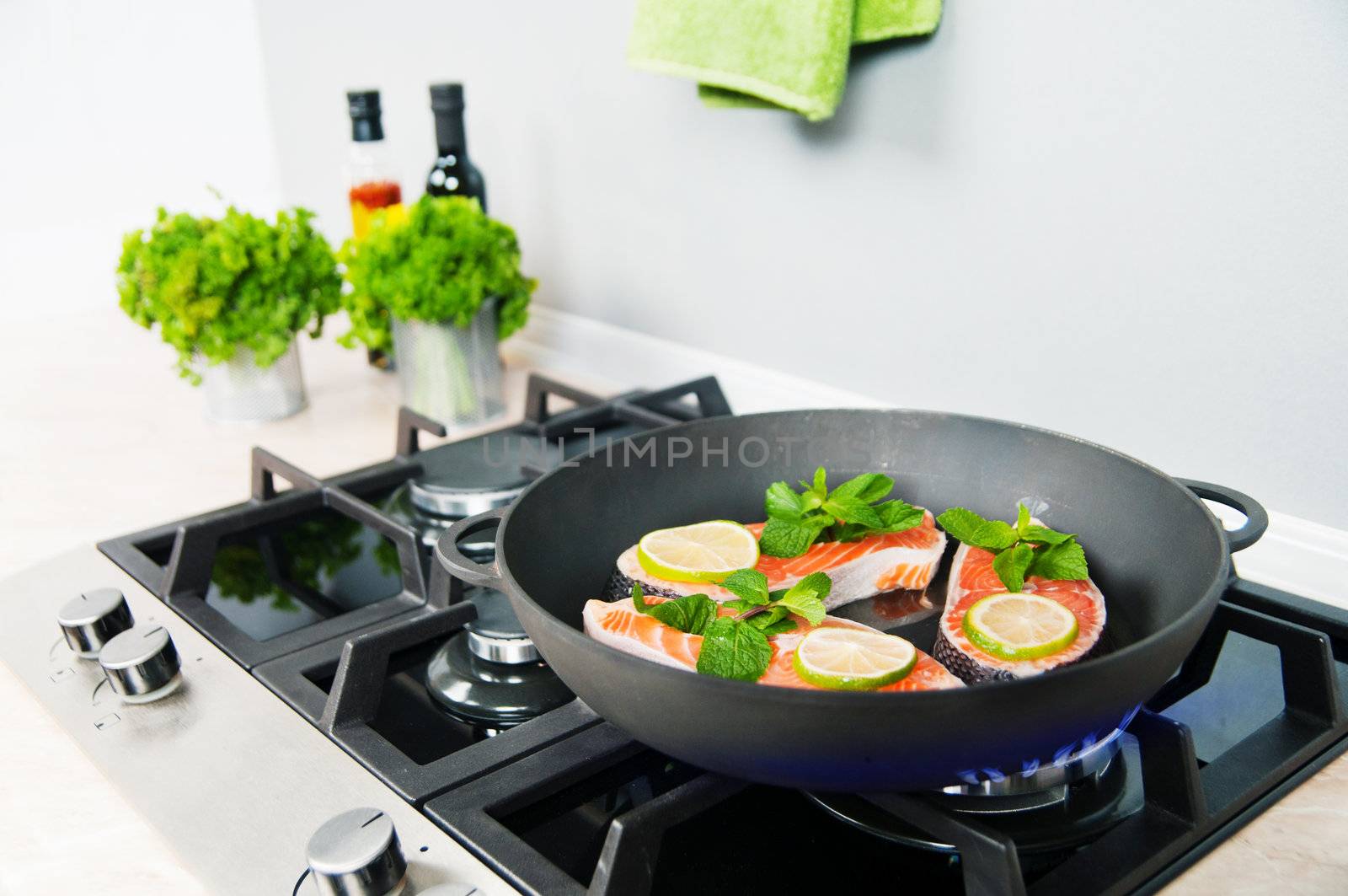 Red fish with mint and lemon prepared in a black skillet in the kitchen