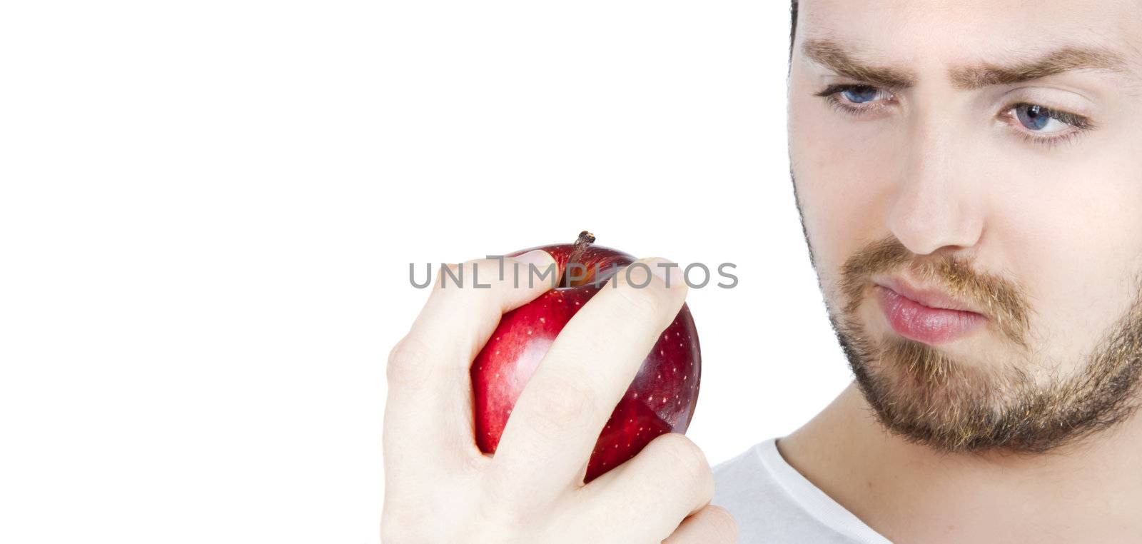 Young blonde man holding and staring at a red apple isolated