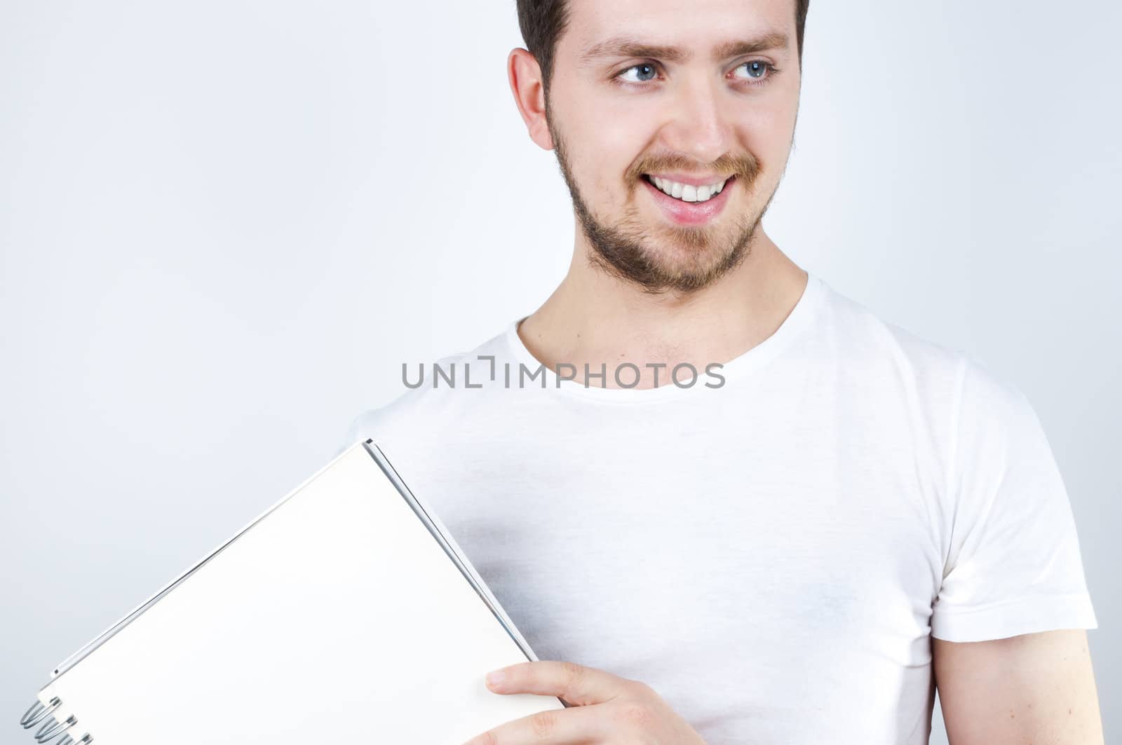 Isolated image of a young blonde man holding a notebook and smiling happily