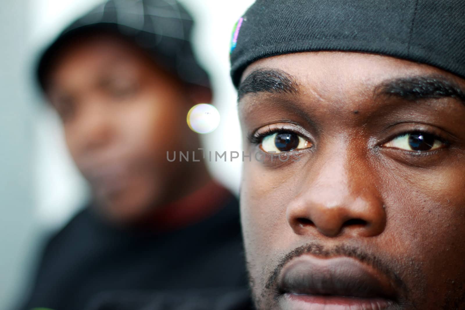 Two young African Americans. A person can be seen in the background out of focus