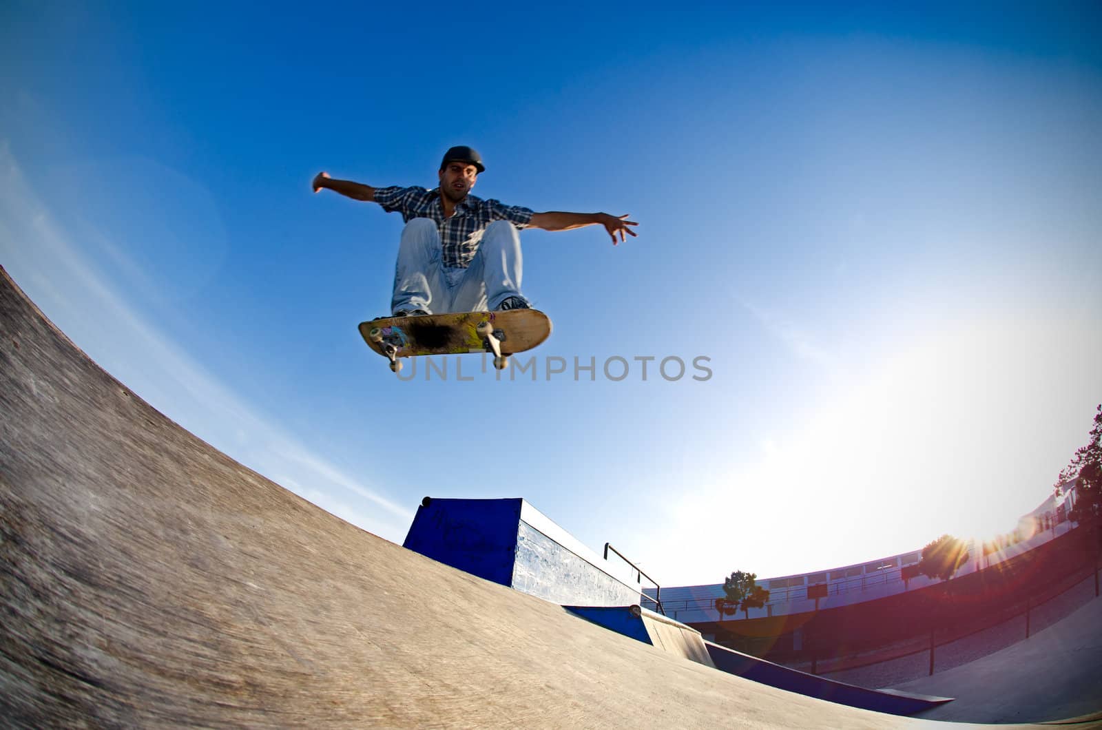 Skateboarder flying over a ramp on sunset at the local skatepark.