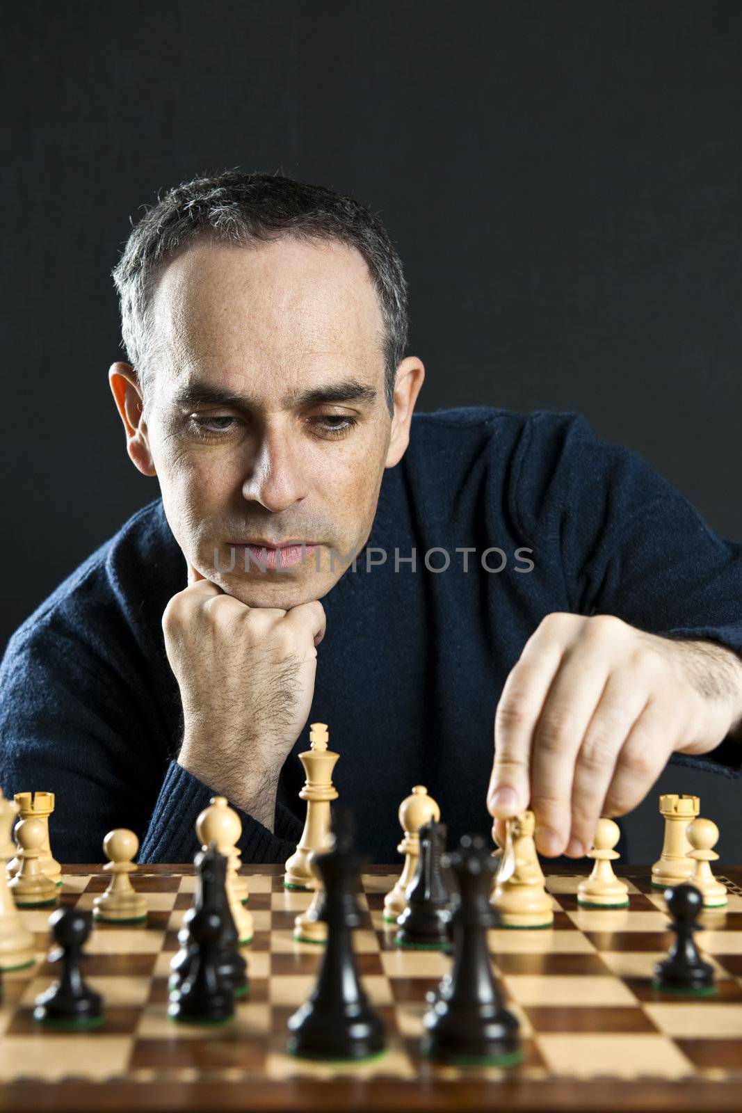 Man moving a chess piece on wooden chessboard