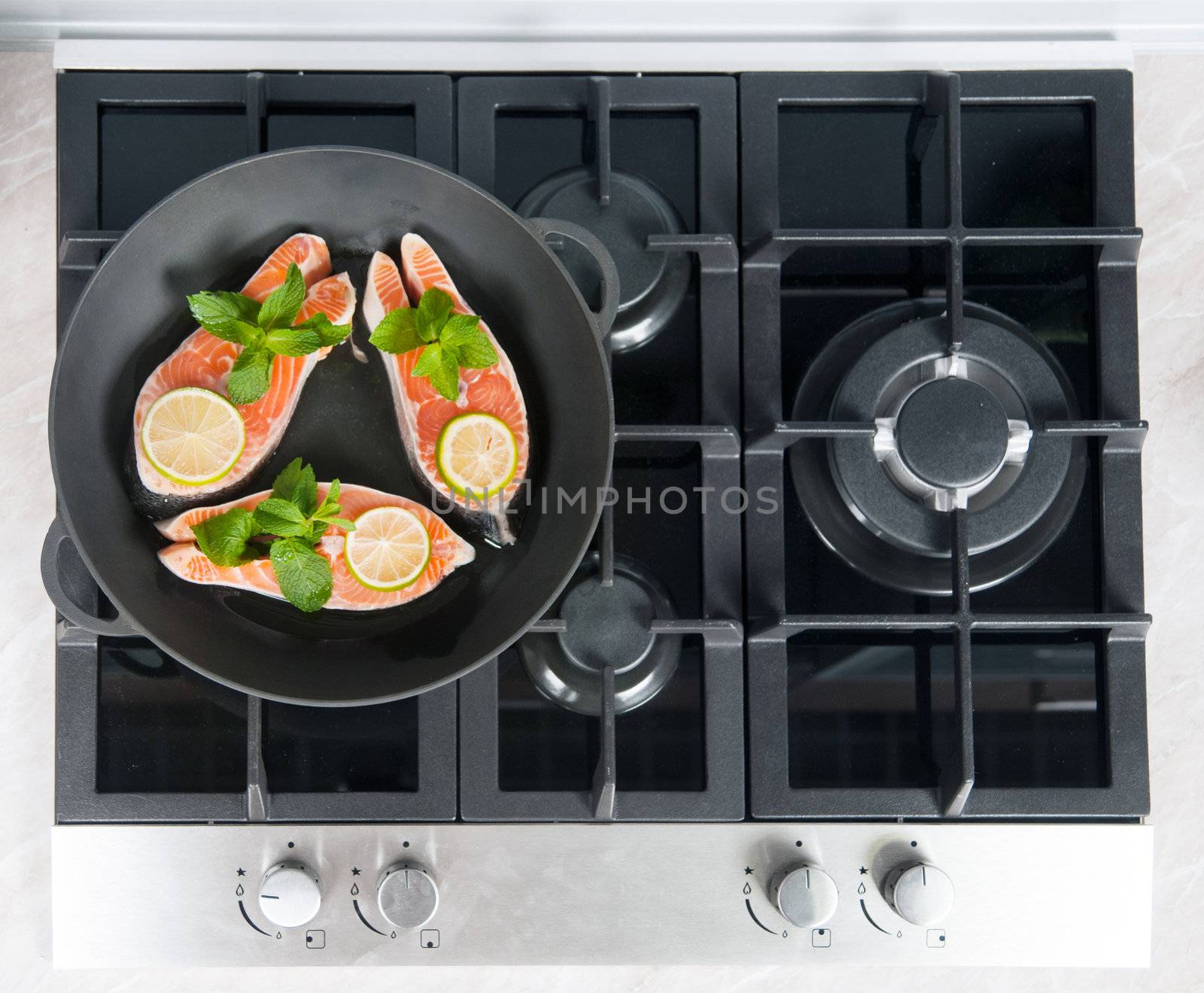 Red fish with mint and lemon prepared in a black skillet in the kitchen