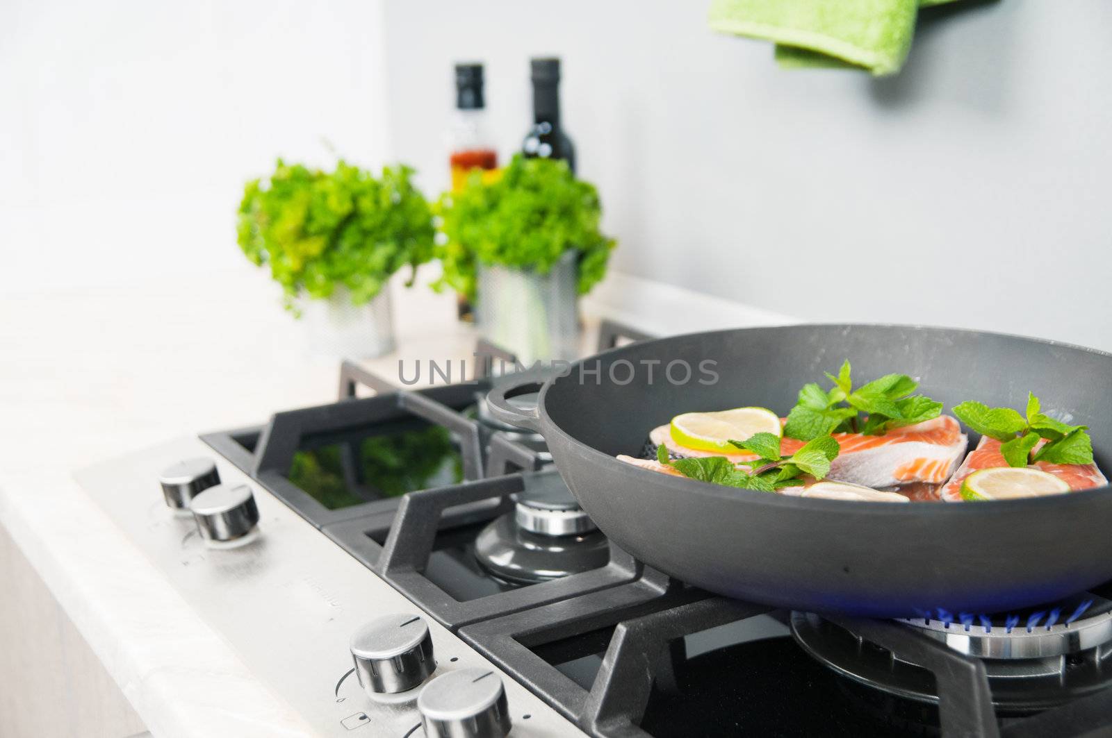 Red fish with mint and lemon prepared in a black skillet in the kitchen