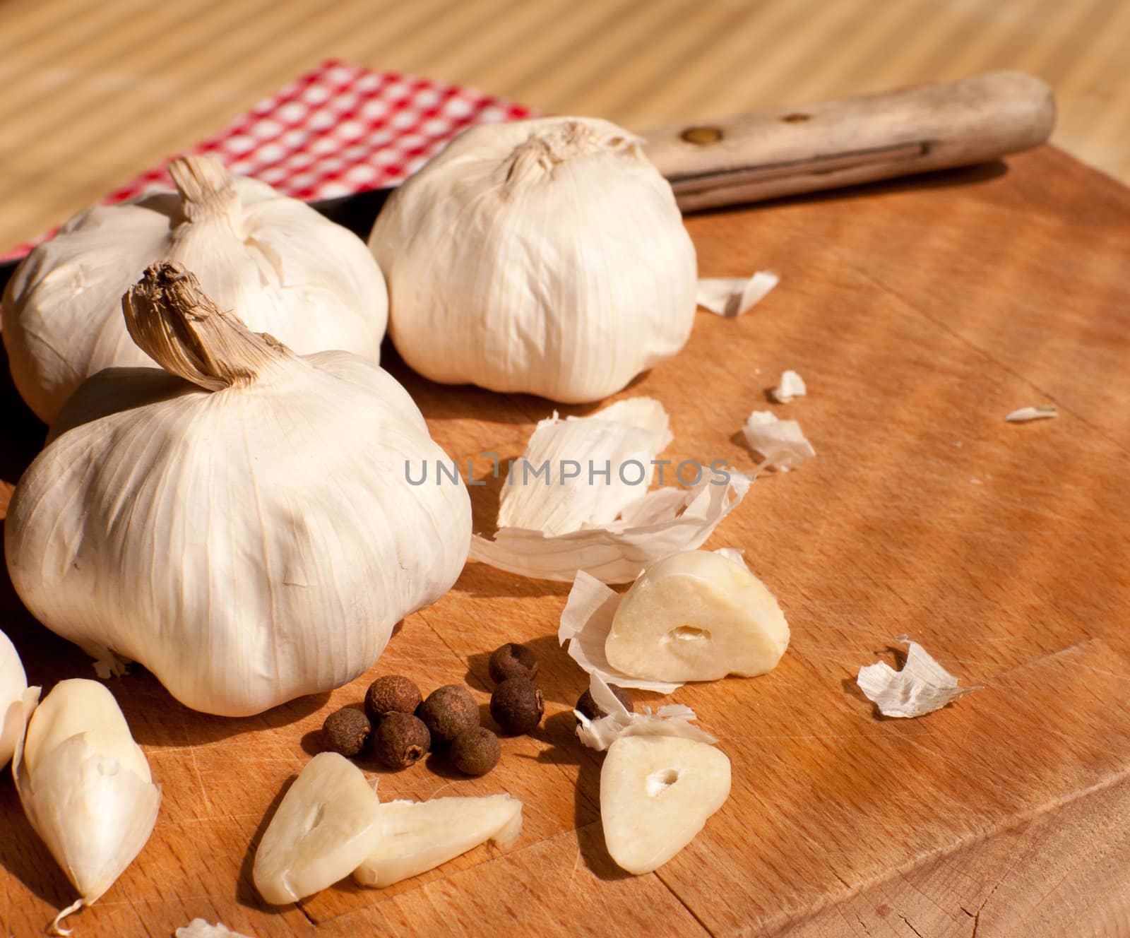 Garlic, kitchen knife and allspice on chopping board