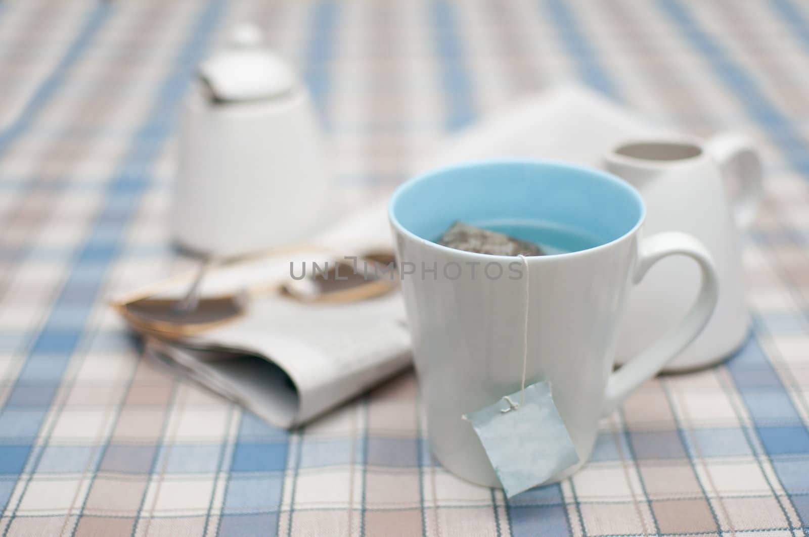 Mug of Tea and Newspapers with Sunglasses on Table