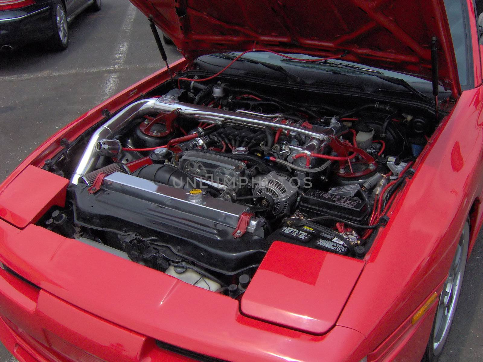 A red turbo sports car with a lot of work done to it under the hood.  