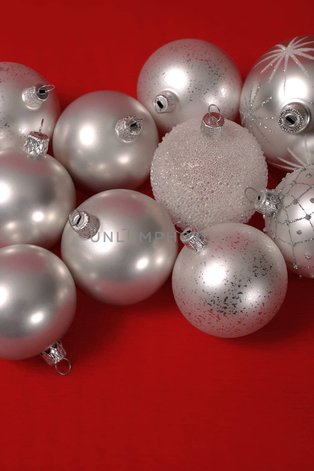 Silver Christmas balls on red background.  Space for text top and bottom.
