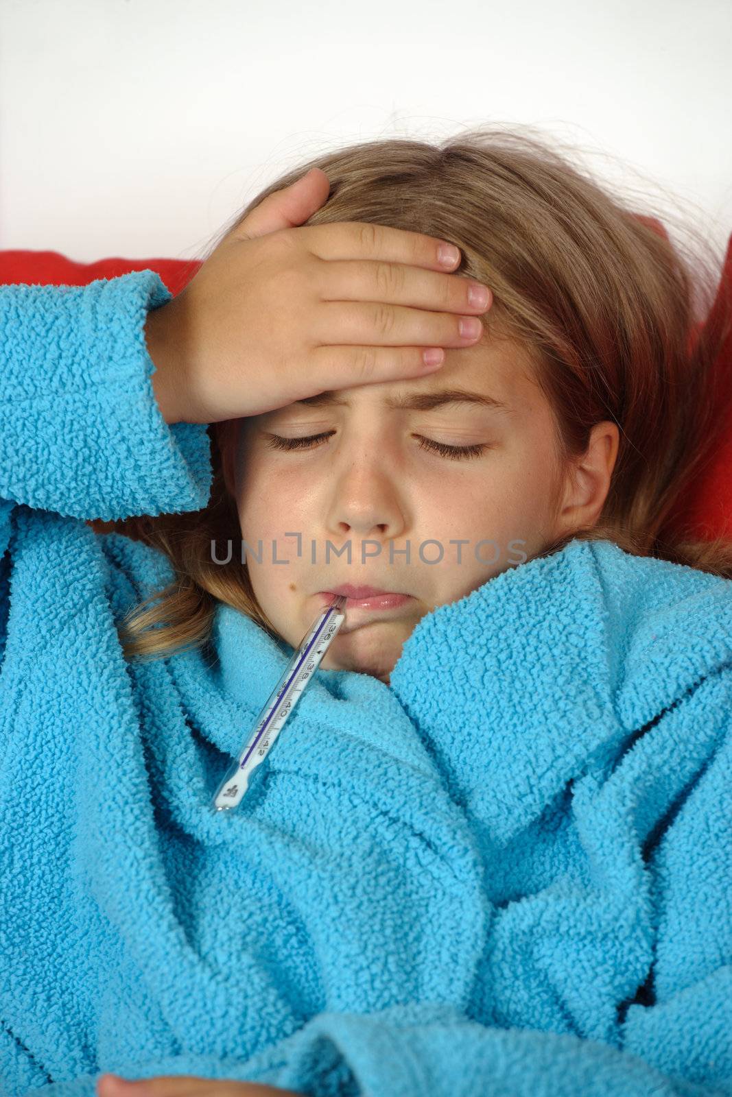 Sick child with thermometer and hand on her forehead.
