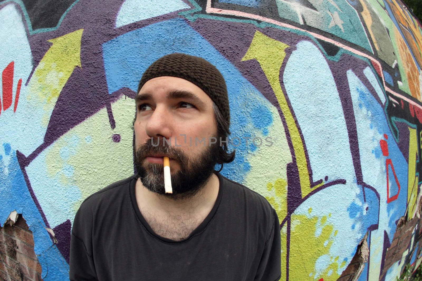 A homeless man on the city streets, smoking and pondering.  Shot with fish-eye lens.
