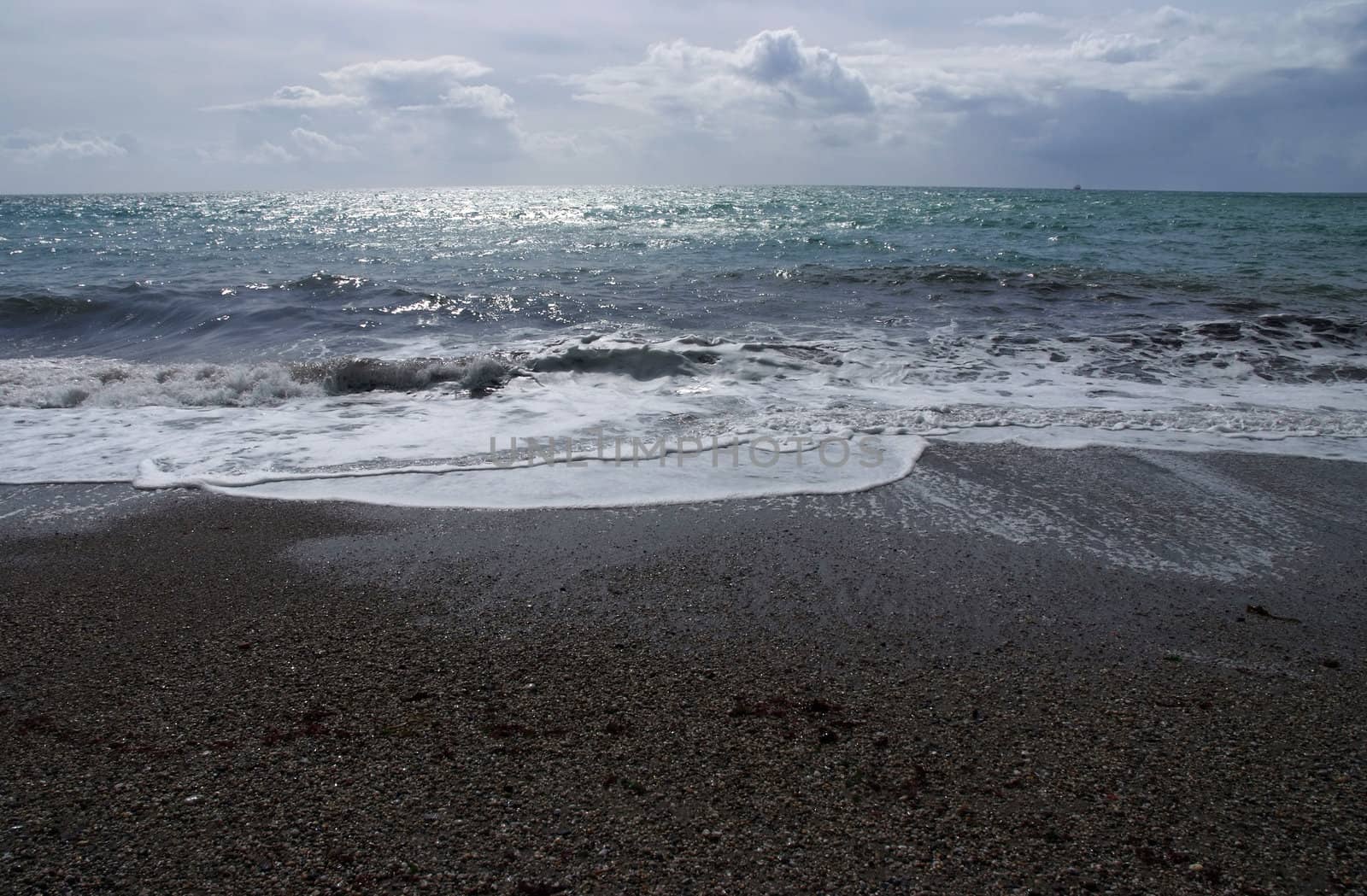 The coastline light with moonlight with the sea coming in over a shingle beach