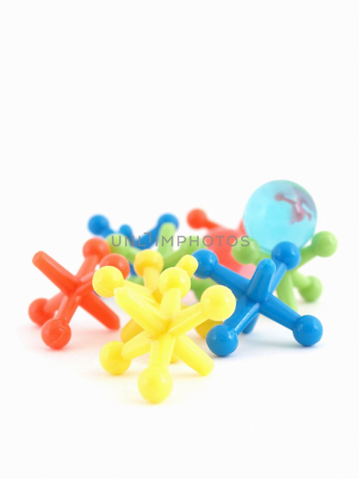 Colorful plastic toy jacks and a blue bouncy ball isolated on a white background